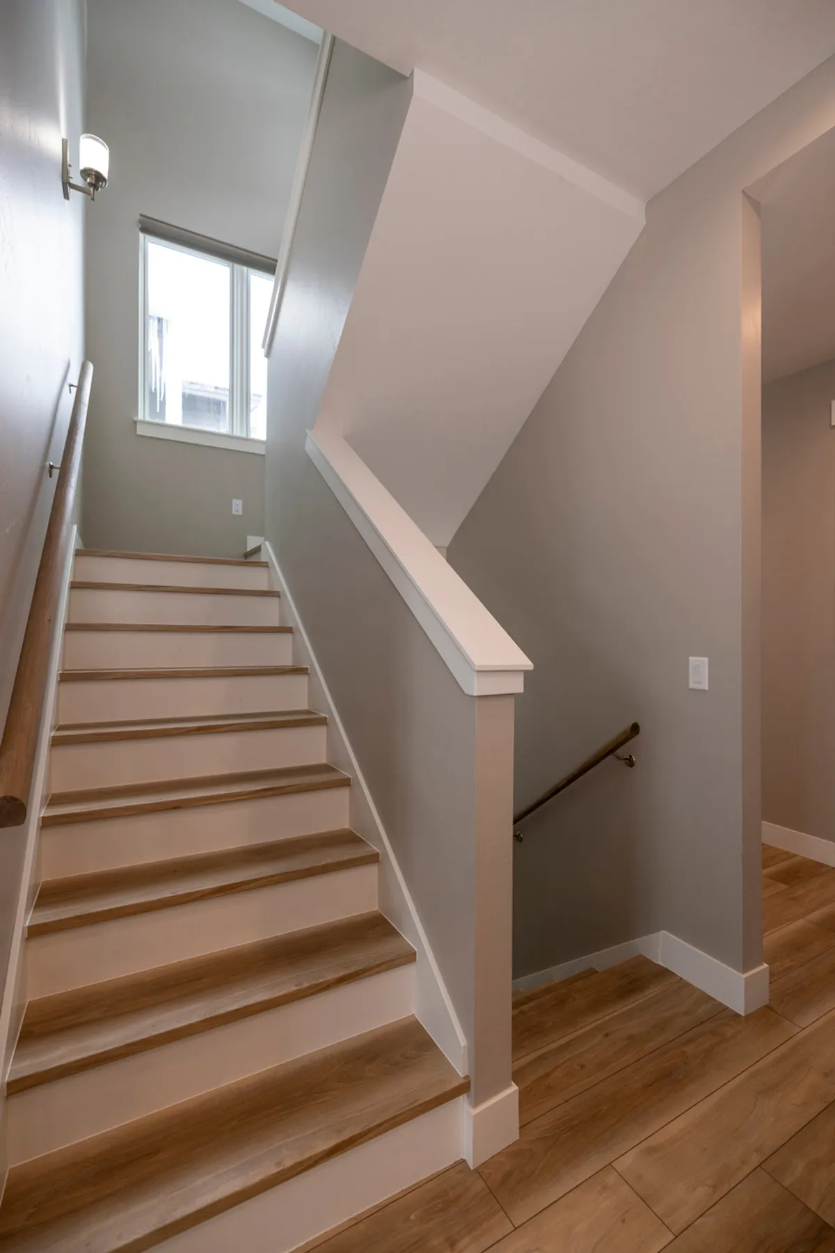 This image shows an inviting staircase with a large window, letting in natural light and offering a glimpse toward the outdoors. The handrail and the gentle brightness create a transition space that hints at the flow between indoor comfort and the mountain landscape just beyond.
