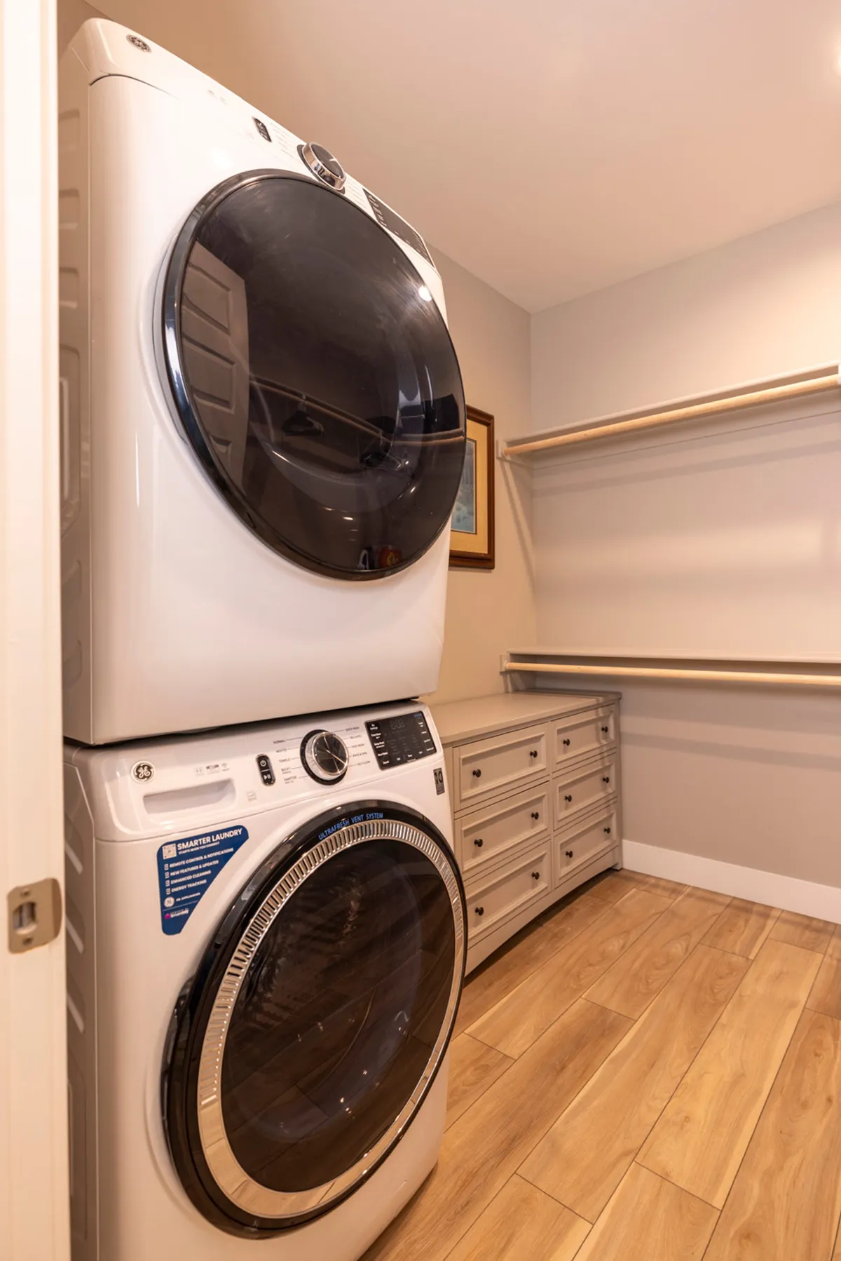 This image features a stacked washer and dryer unit complemented by storage drawers and framed artwork. The space is bright and organized, exuding a sense of practicality and efficiency, perfect for handling laundry after an active day outdoors.