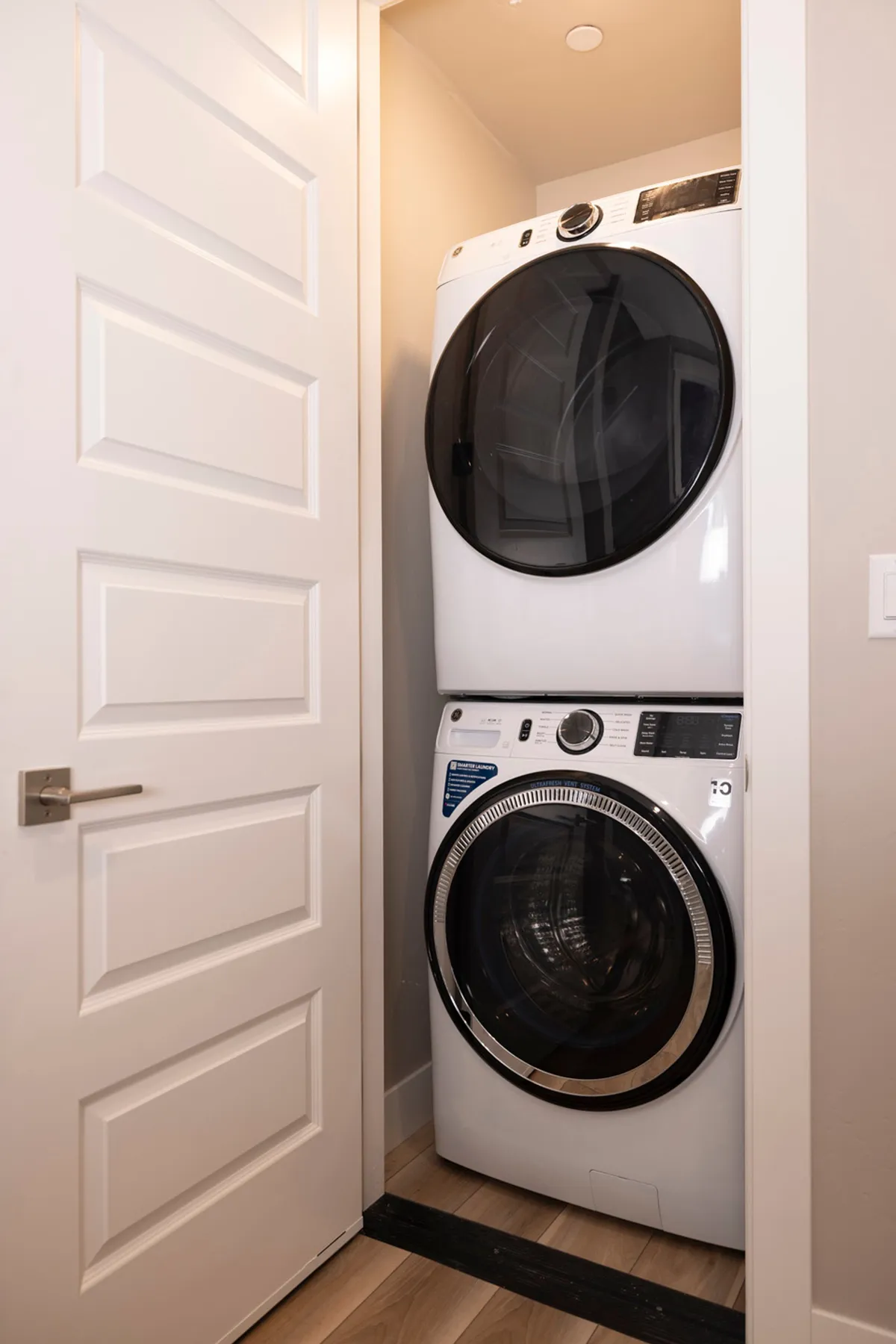 A second dedicated laundry area with stacked washer and dryer, white cabinetry, and a modern finish. The setup is neat and accessible, showcasing the dual laundry center feature ideal for larger groups or families.
