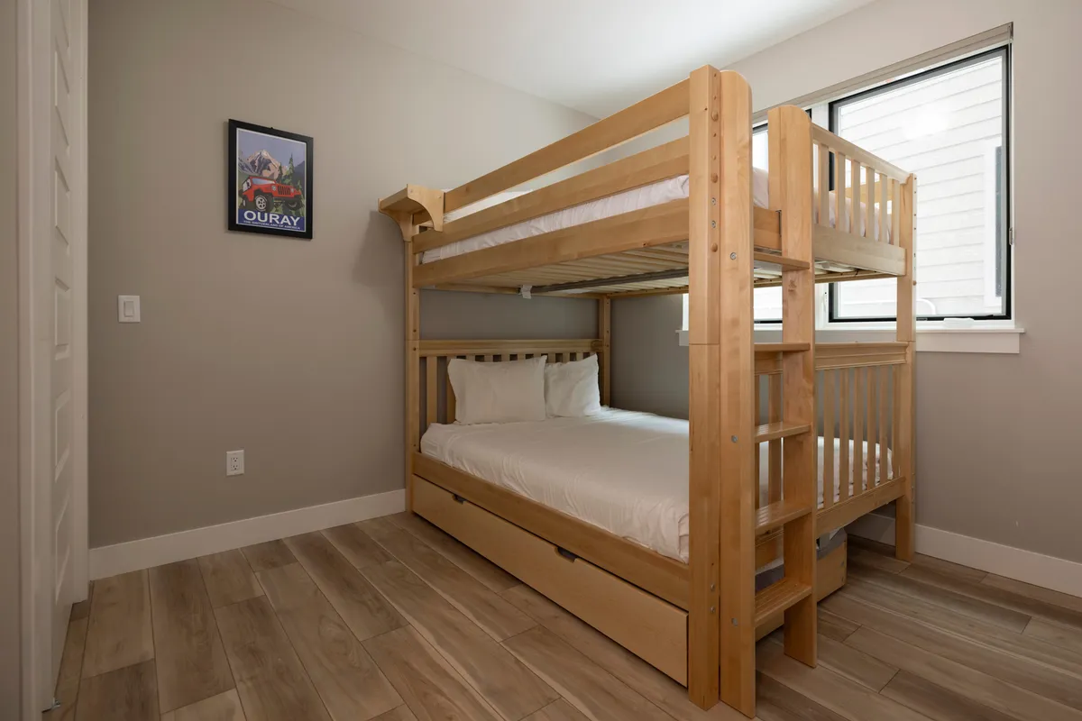 A cozy bedroom designed for kids or extra guests, featuring a stylish bunk bed by a sunlit window. Thoughtful wall art injects a playful touch, making the space ideal for sleepovers and family stays.