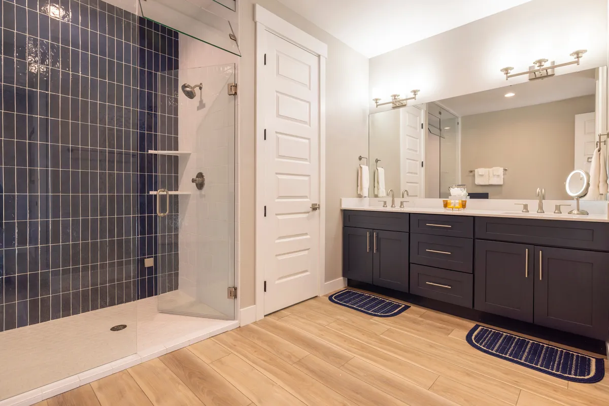 A modern bathroom with a glass steam shower enclosure, double vanity sinks, and a blue tiled accent wall. The space looks luxurious and inviting, perfect for relaxation and self-care after a day outdoors.