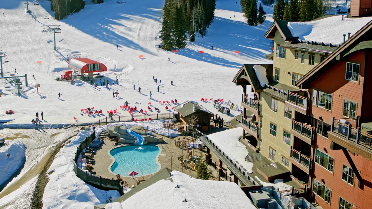 A vibrant winter scene at Purgatory Resort, showcasing energetic skiers and snowboarders on the slopes, a welcoming lodge with classic mountain architecture, and a swimming pool steaming in the cold air. The image captures both the thrill of snowy adventure and the comfort of après-ski relaxation.